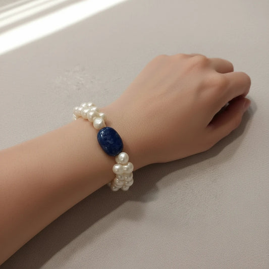 CREATIVE PEARLS double-strand freshwater pearl bracelet featuring a polished deep blue center gemstone on a wrist.